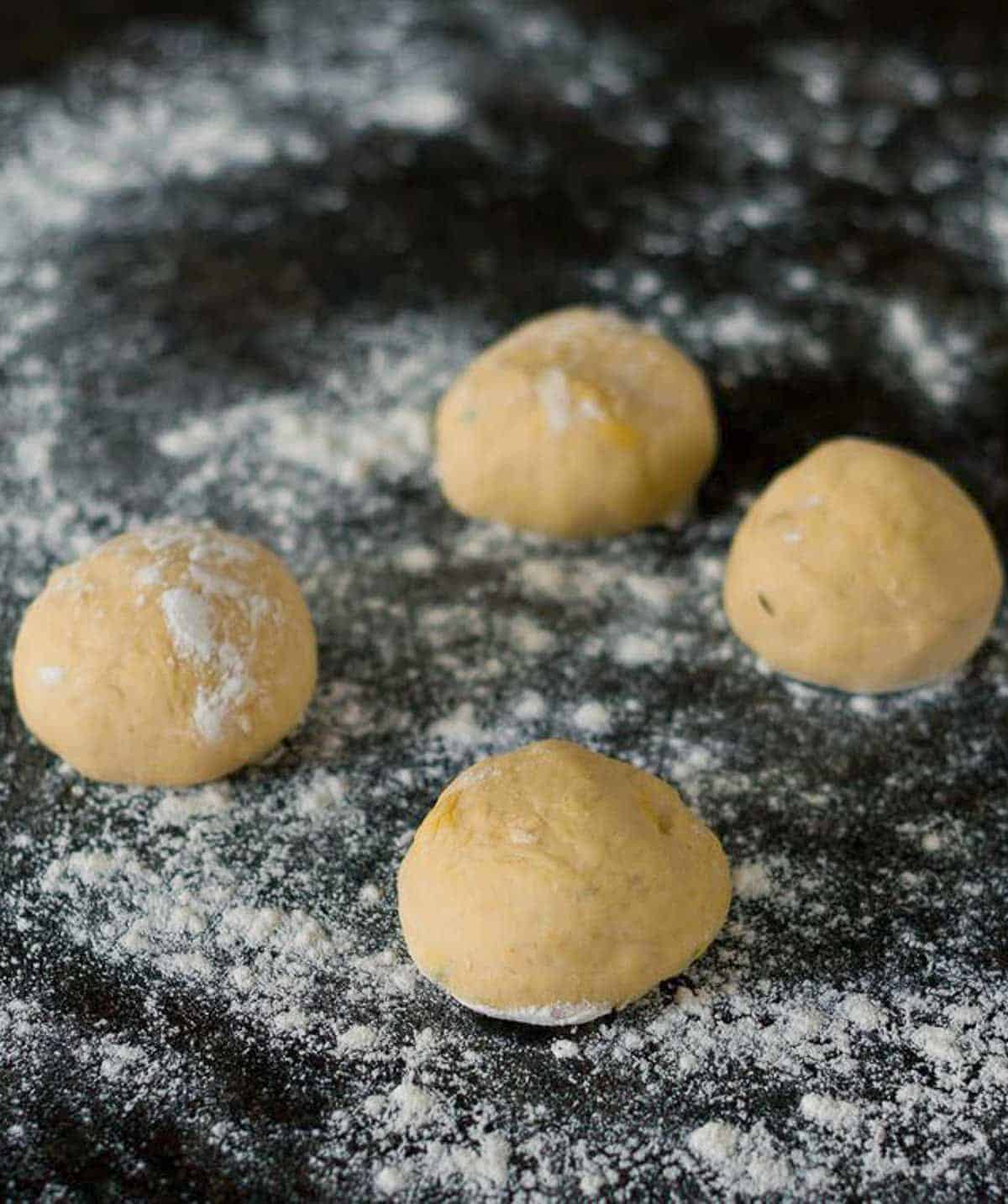 4 dough balls on a floured surface.