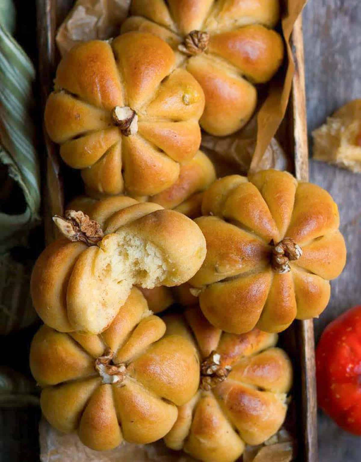 pumpkin dinner rolls in a wooden tray.