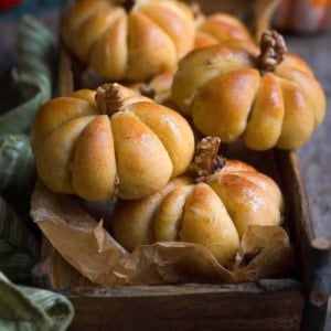 pumpkin bread rolls piled up in a wooden tray.