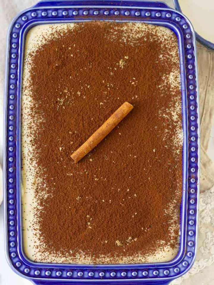 masala chai tiramisu in a blue dish with chai masala and other spices around.